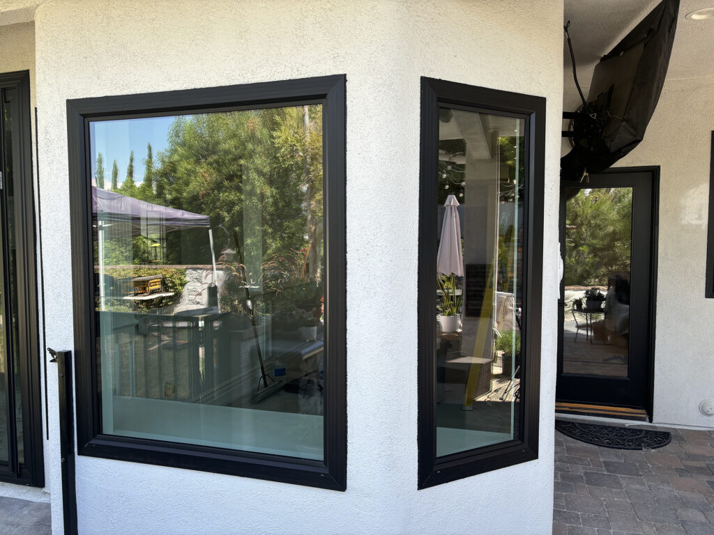 An exterior view of two fixed windows side by side, both in a Designer Black™ finish.